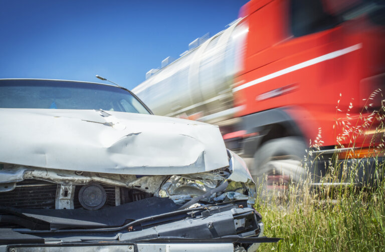 Crashed car and red truck passing.
