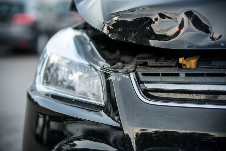 Close-up of car with front-end damage and dented hood