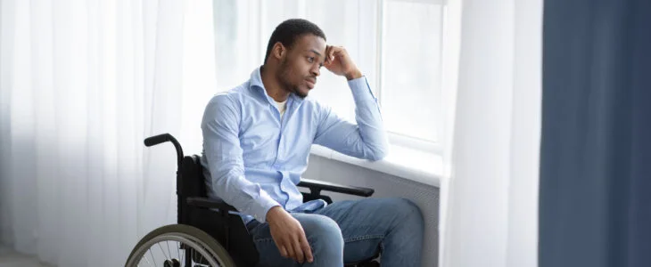 Young man sitting in a wheelchair looking out a window